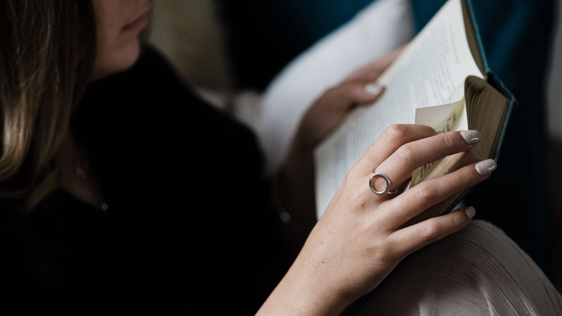 Person holding a book with a small object inside, wearing a ring.